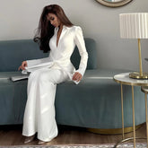 Woman in a white outfit sitting on a gray sofa in a modern living room.
