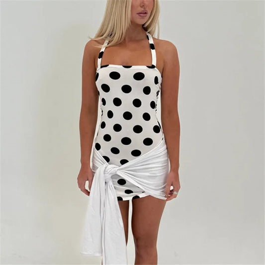 Woman wearing a black and white polka dot swimsuit cover-up on a plain background