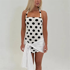 Woman wearing a black and white polka dot swimsuit cover-up on a plain background