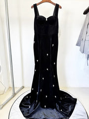 Black velvet mermaid maxi dress with spaghetti straps and beaded embellishments, displayed on a hanger.