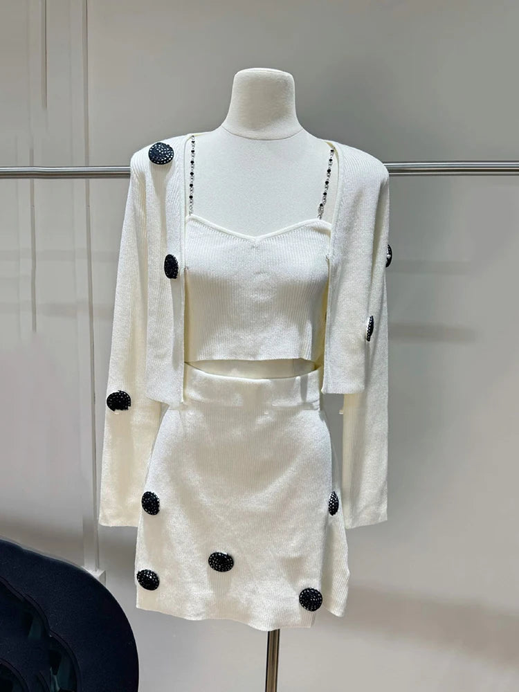 White outfit with black polka dots on a mannequin against a neutral background