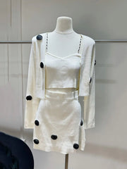White outfit with black polka dots on a mannequin against a neutral background