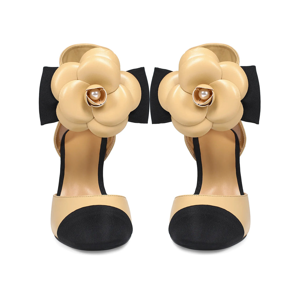 Beige high-heeled shoes with floral design and black accents on a white background