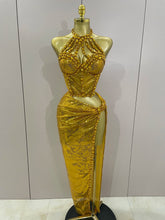 Gold evening gown on a mannequin against a plain background