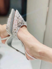 Sparkly high-heeled shoes worn by a person sitting on a chair.