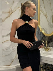 Woman in a black dress holding a Chanel clutch in a marble bathroom.