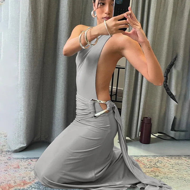 Woman in a gray dress taking a mirror selfie in a room with curtains and a rug.