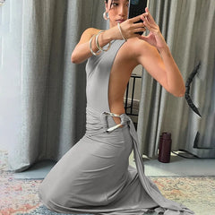 Woman in a gray dress taking a mirror selfie in a room with curtains and a rug.