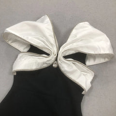 White bow on a black dress against a gray background