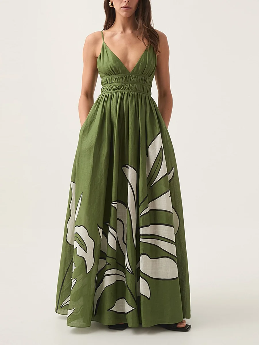 Full view of a person wearing a green floral print V-neck shirred empire waist maxi dress with hands in pockets