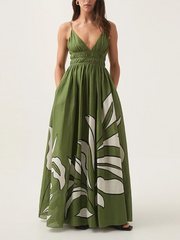 Full view of a person wearing a green floral print V-neck shirred empire waist maxi dress with hands in pockets