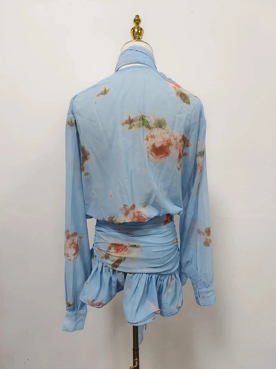 Light blue floral blouse with ruffled bottom on a mannequin against a white background