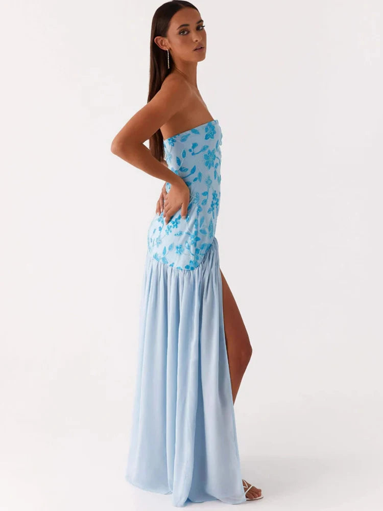 Woman wearing a strapless dress with blue floral top and light blue skirt on a white background