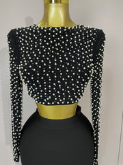 Black crop top with pearl embellishments on a mannequin against a plain background