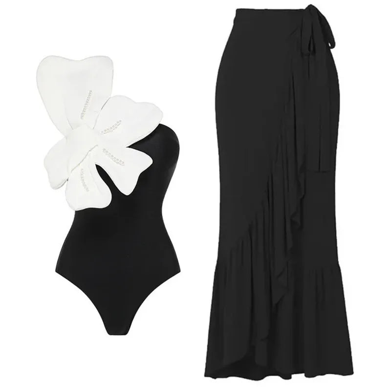 Black one-piece swimsuit with a white butterfly detail and a black ruffled maxi skirt.