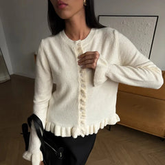 Woman wearing a cream-colored cardigan in an indoor setting