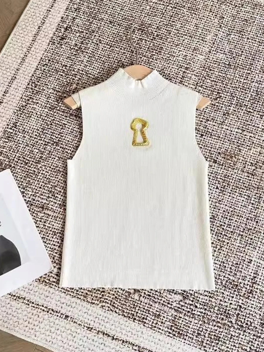 White sleeveless top with a gold emblem on a textured surface