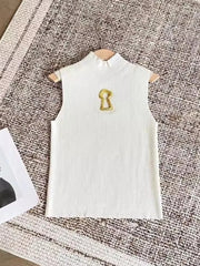 White sleeveless top with a gold emblem on a textured surface