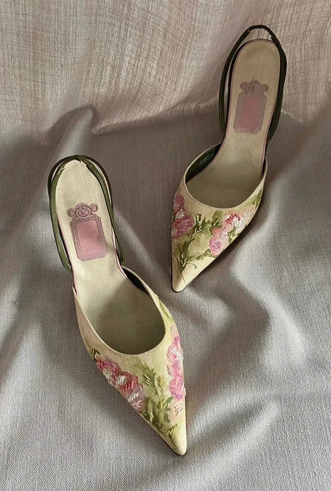 Pair of floral high-heeled shoes on a light fabric background