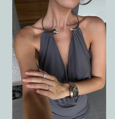 Woman wearing a gray halter top with jewelry on a neutral background