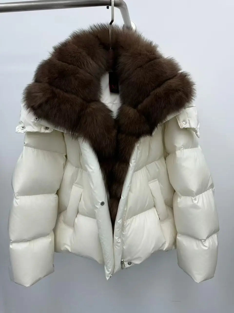 White puffer jacket with a large brown fur hood on a gray background