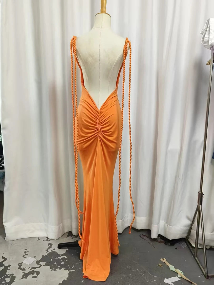 Orange evening gown with long train on a mannequin against a white curtain background