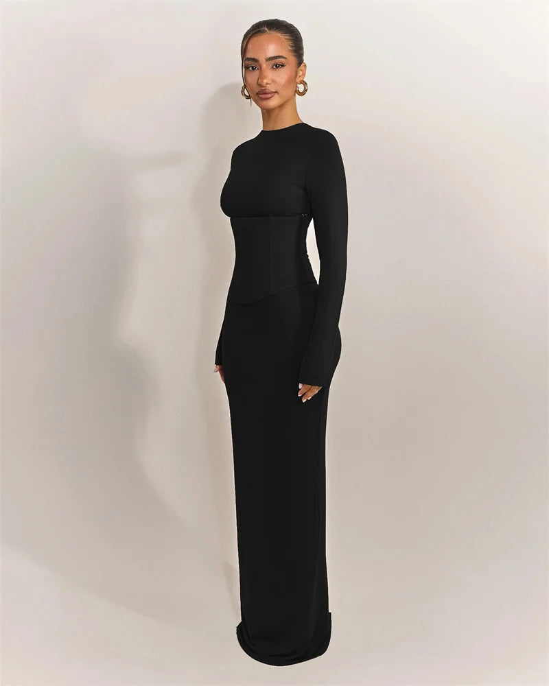 Woman wearing a black long-sleeve gown against a plain background