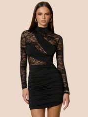 Black lace dress worn by a model on a beige background