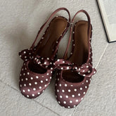Brown polka dot slingback pumps with a bow accent.