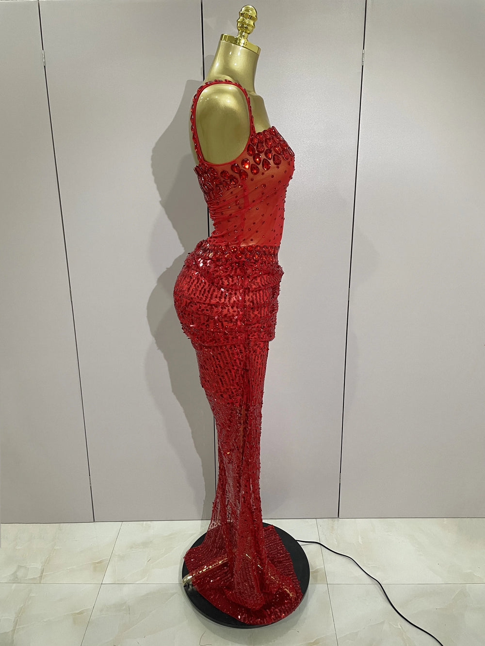 Red sequin dress on a mannequin against a white wall.