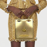 Gold sculptural face structured tote bag with top handle.