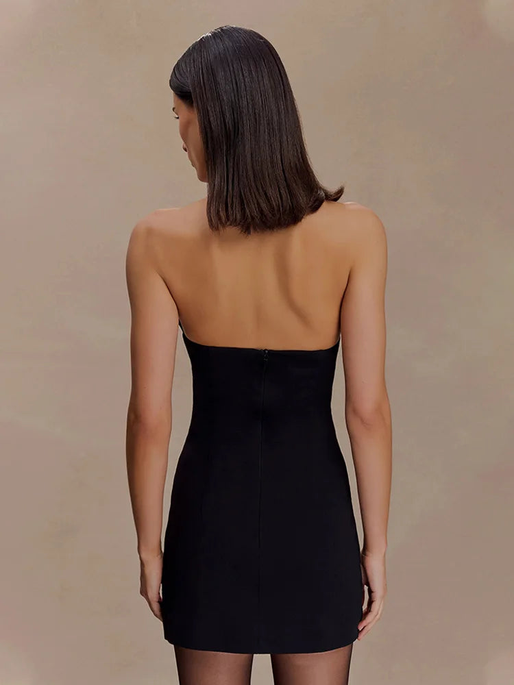 Woman wearing a black strapless dress against a beige background