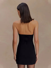 Woman wearing a black strapless dress against a beige background