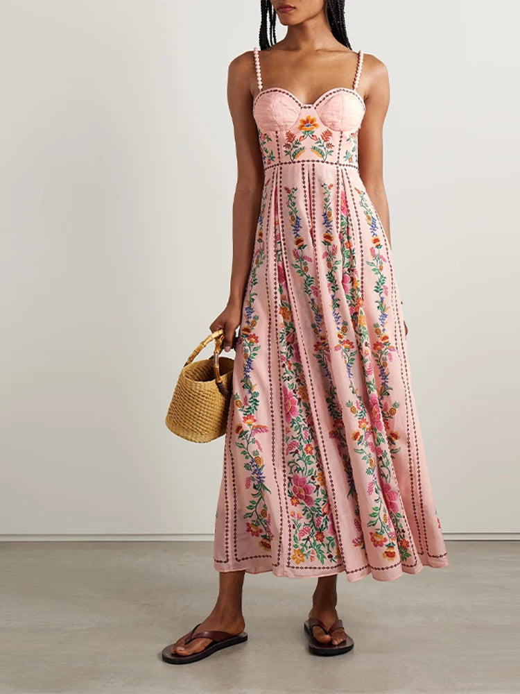 Woman wearing a pink floral dress holding a straw bag against a plain background