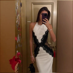 Person wearing a white and black lace dress taking a mirror selfie.