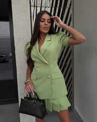 Woman in a green suit standing against a wall with a geometric design.