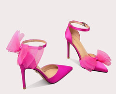Pink high-heeled shoes with large bows on a white background