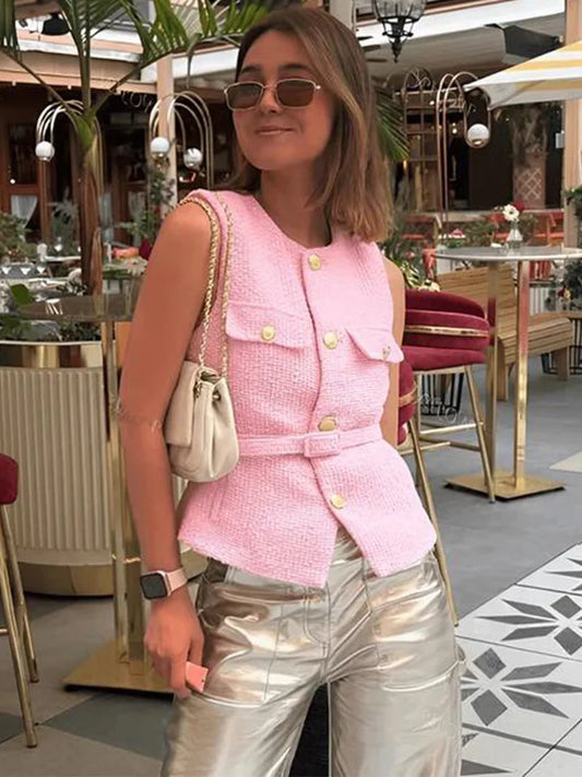 Woman wearing a pink vest and silver pants in an outdoor setting