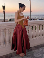 Woman in a mustard top and red skirt standing on a balcony with ocean view.