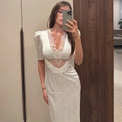 Woman taking a mirror selfie wearing a white lace dress.