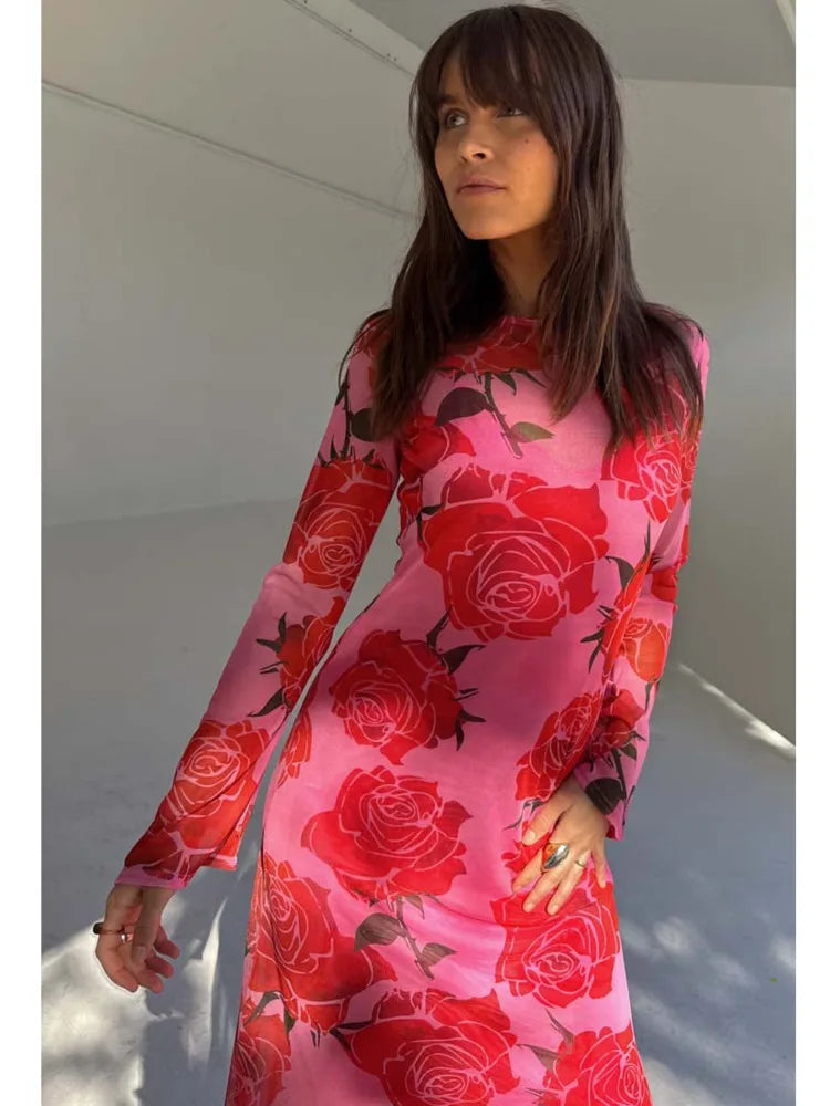 Person wearing a pink dress with red floral patterns against a white background