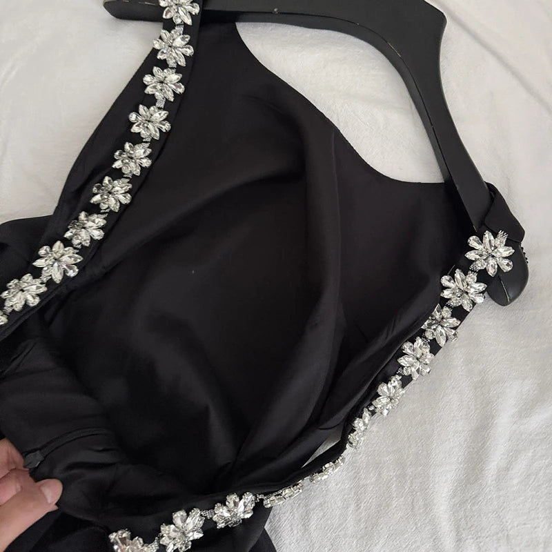Close-up of the crystal flower embellishment on the spaghetti strap of a black dress