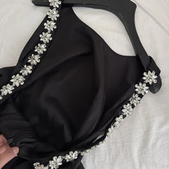 Close-up of the crystal flower embellishment on the spaghetti strap of a black dress
