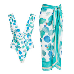 White one-piece swimsuit with abstract blue and green dots and a matching wrap skirt.