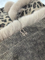 Close-up of a textured fabric with a leopard print pattern and a visible brand logo.
