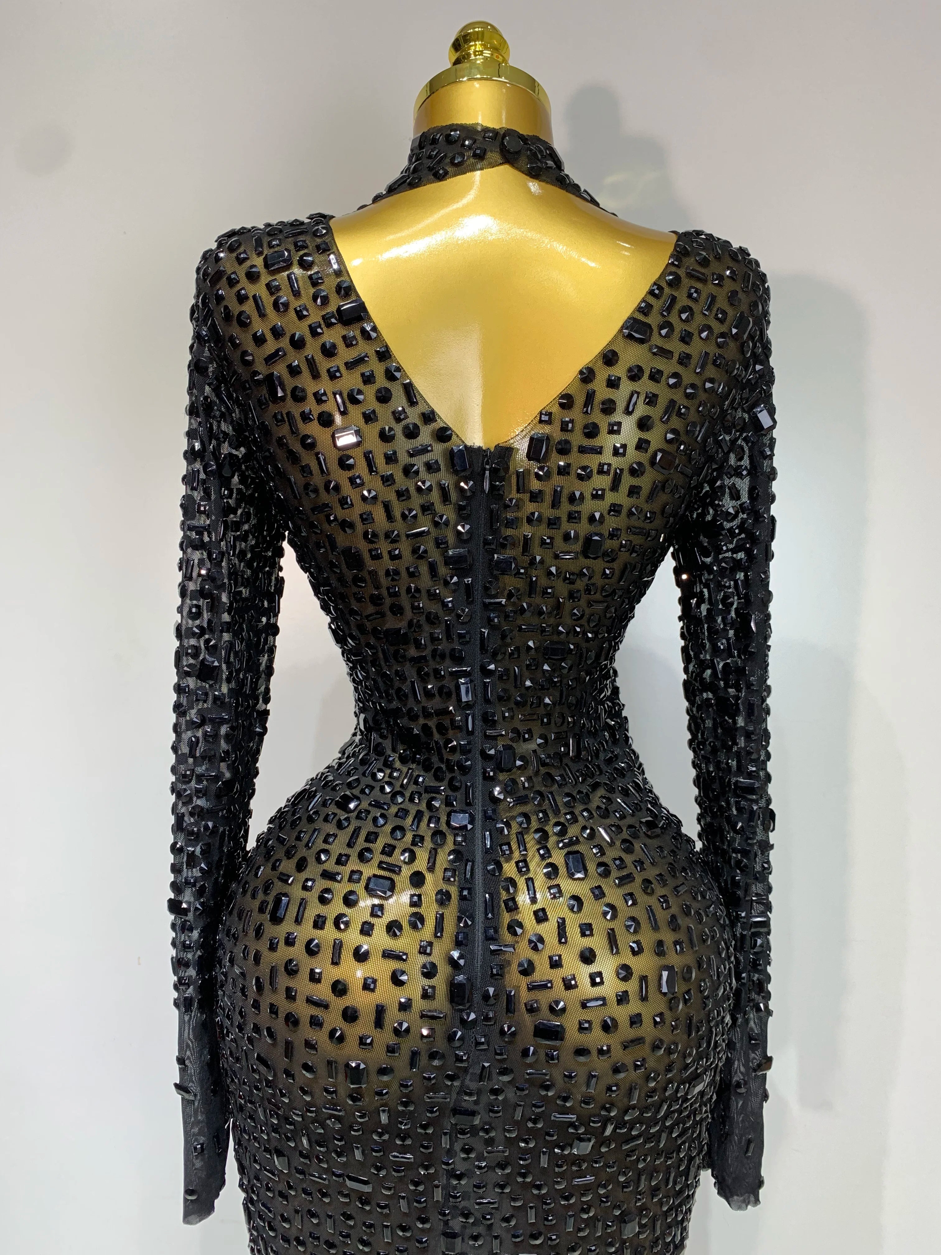 Black beaded dress on a mannequin against a white background