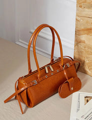 Brown leather handbag on a light wooden floor with a neutral wall background