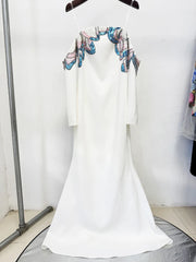 White dress with floral embroidery on a hanger against a white background