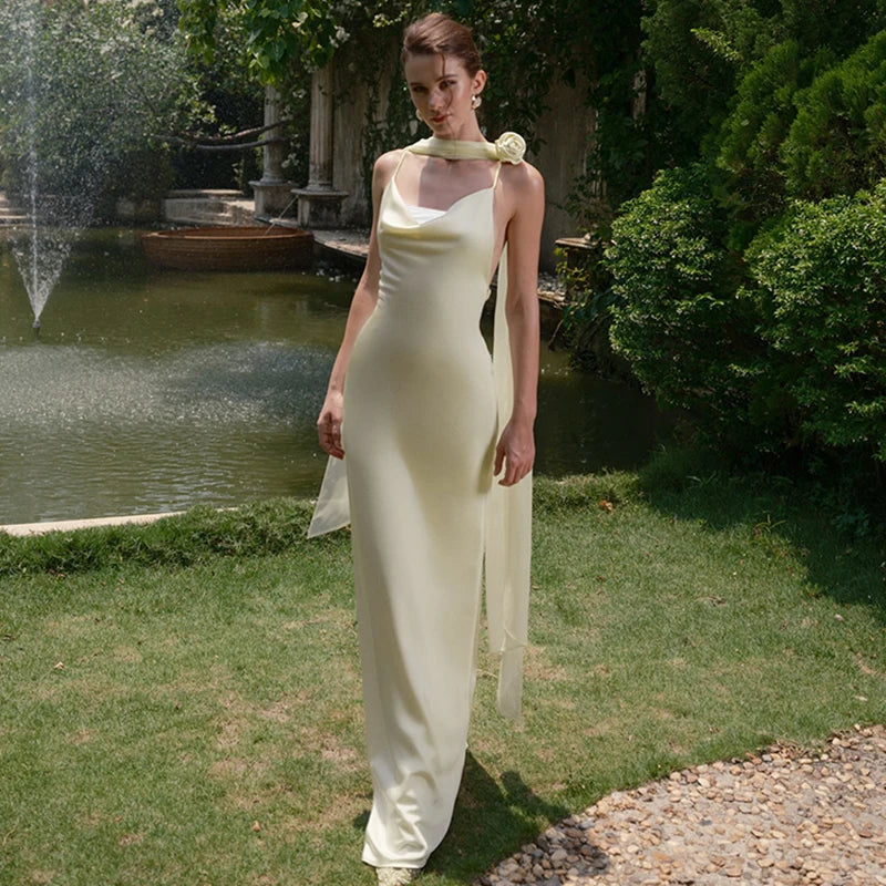 Woman in a white dress standing in a garden with a fountain in the background