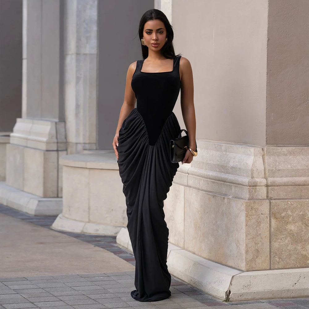 Woman in a black evening gown standing against classical architecture.